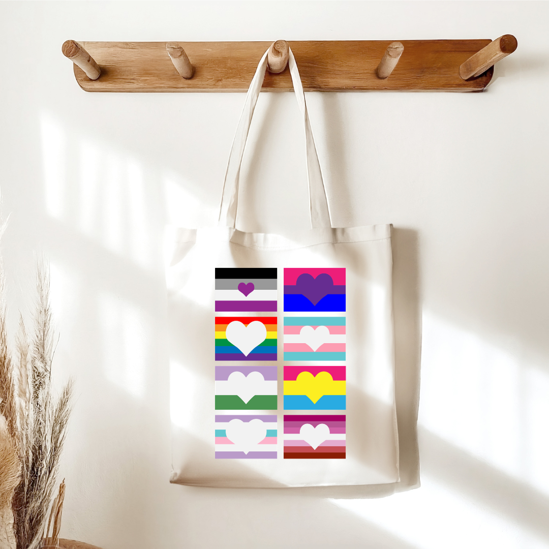canvas pride tote bag with rainbow heart flags design hanging on wall