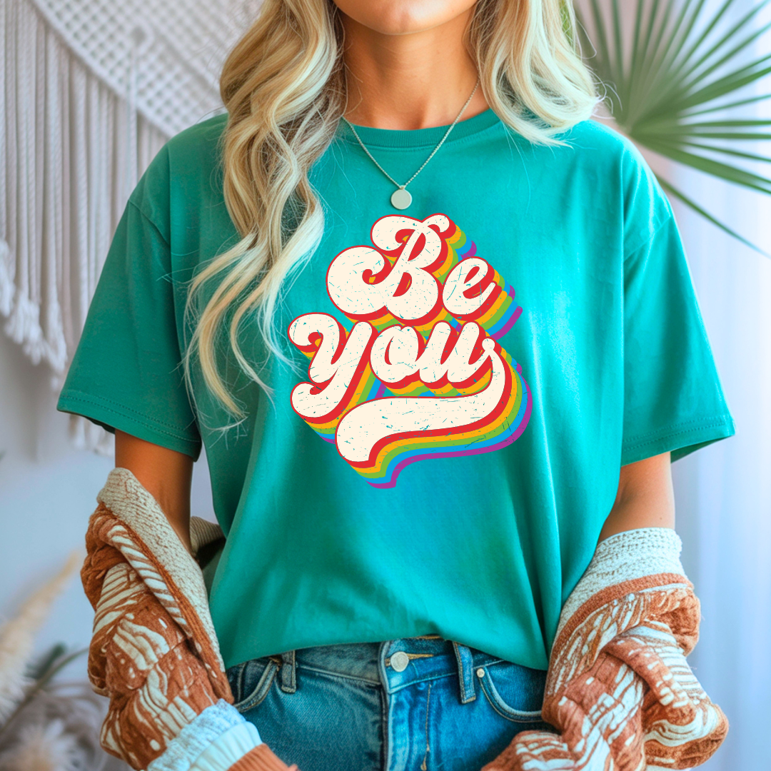 person wearing jade be you pride shirt with retro rainbow lettering design