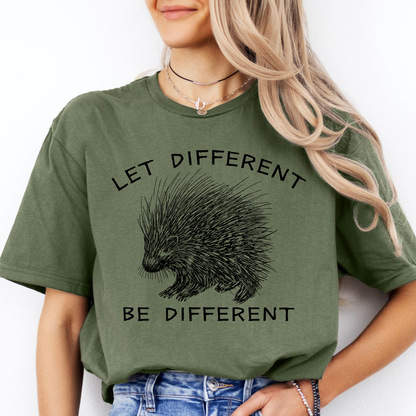 A woman wearing an military green graphic t-shirt with a black porcupine illustration and the text 'LET DIFFERENT BE DIFFERENT'.