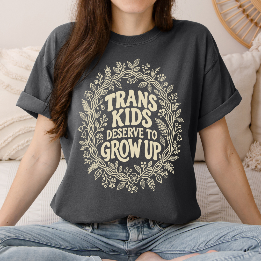 Woman wearing a vintage pepper Trans Kids Deserve to Grow Up t-shirt with cream botanical design