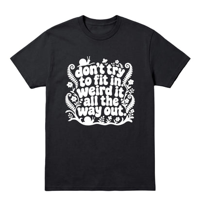 A black short-sleeve crewneck t-shirt with a white graphic text print that reads 'don't try to fit in weird it all the way out' decorated with whimsical doodles of flowers, snails, and ferns, shown on a plain white background.