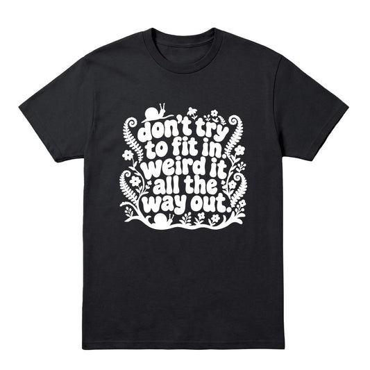 A black short-sleeve crewneck t-shirt with a white graphic text print that reads 'don't try to fit in weird it all the way out' decorated with whimsical doodles of flowers, snails, and ferns, shown on a plain white background.