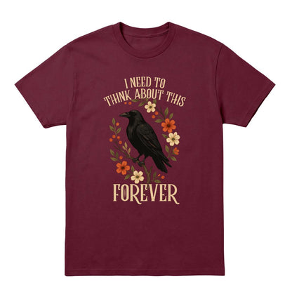 A maroon short-sleeve crewneck t-shirt featuring a graphic of a black raven surrounded by orange, yellow, and white flowers, with the text 'I NEED TO THINK ABOUT THIS FOREVER' in a cream-colored serif font.