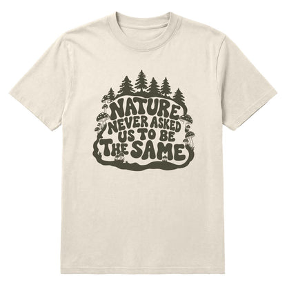 An off-white crewneck t-shirt featuring a dark olive green graphic on the front with the text 'NATURE NEVER ASKED US TO BE THE SAME' surrounded by pine trees and mushrooms.