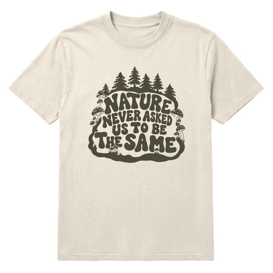 An off-white crewneck t-shirt featuring a dark olive green graphic on the front with the text 'NATURE NEVER ASKED US TO BE THE SAME' surrounded by pine trees and mushrooms.