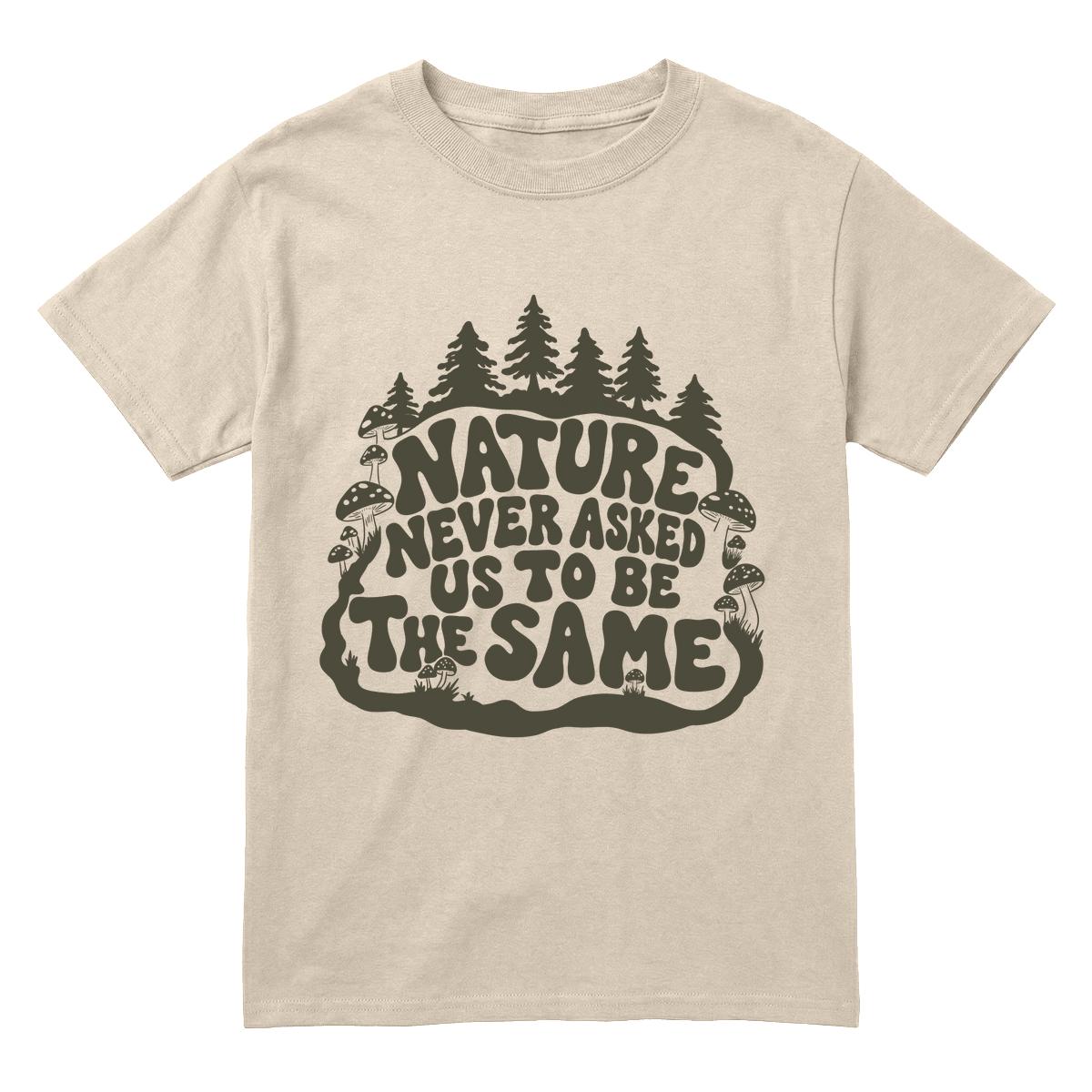 A sand crewneck t-shirt with a dark olive green graphic on the front featuring pine trees and the text 'NATURE NEVER ASKED US TO BE THE SAME'.