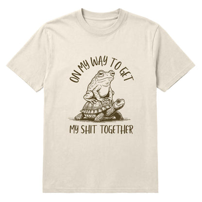 Ivory T-shirt with frog riding a turtle and “On My Way to Get My Shit Together” text