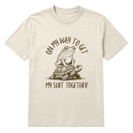 Ivory T-shirt with frog riding a turtle and “On My Way to Get My Shit Together” text