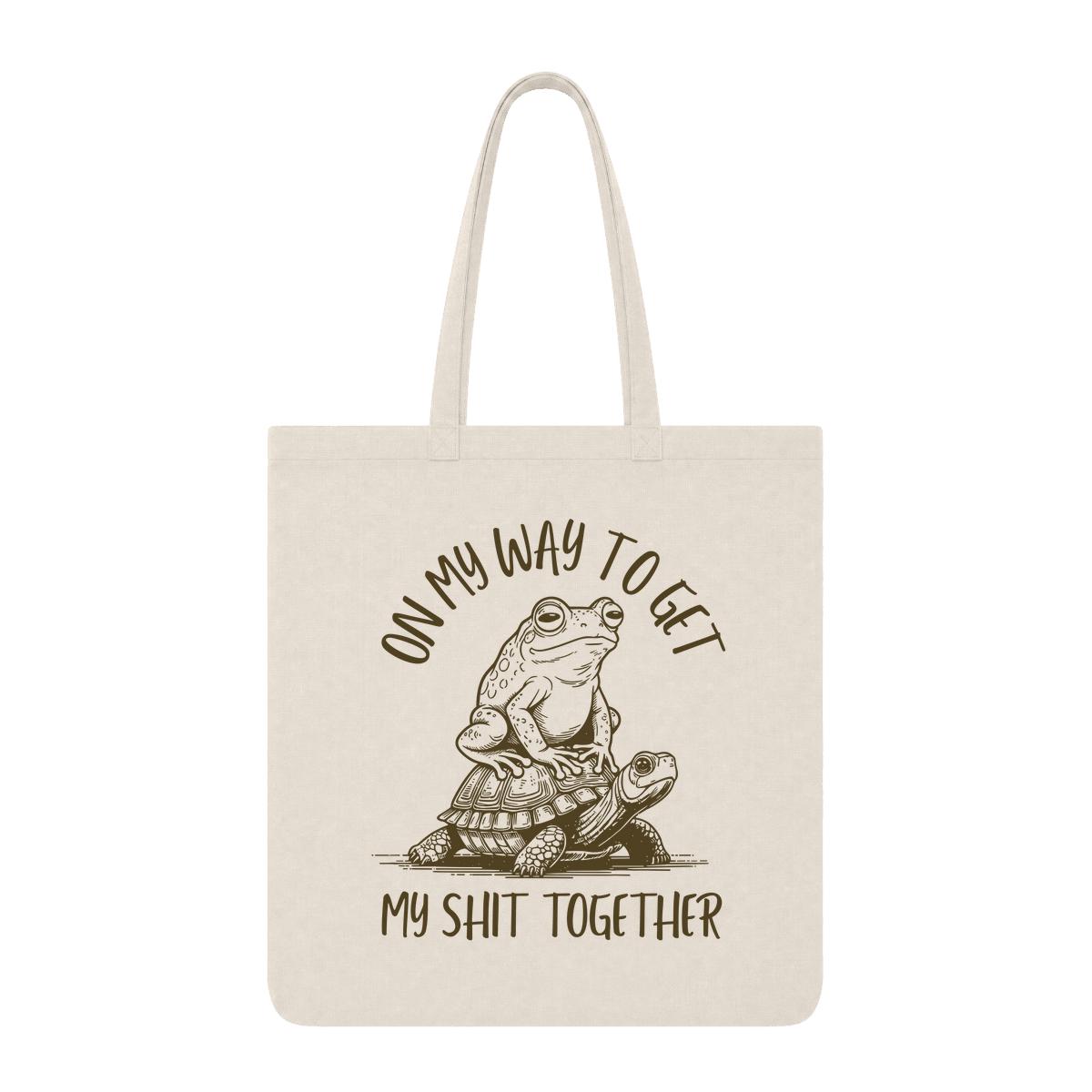Natural tote bag with frog riding a turtle and “On My Way to Get My Shit Together” text