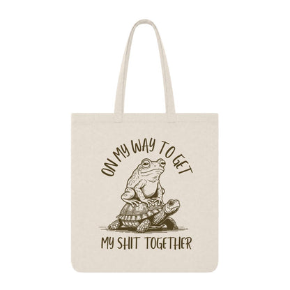 Natural tote bag with frog riding a turtle and “On My Way to Get My Shit Together” text