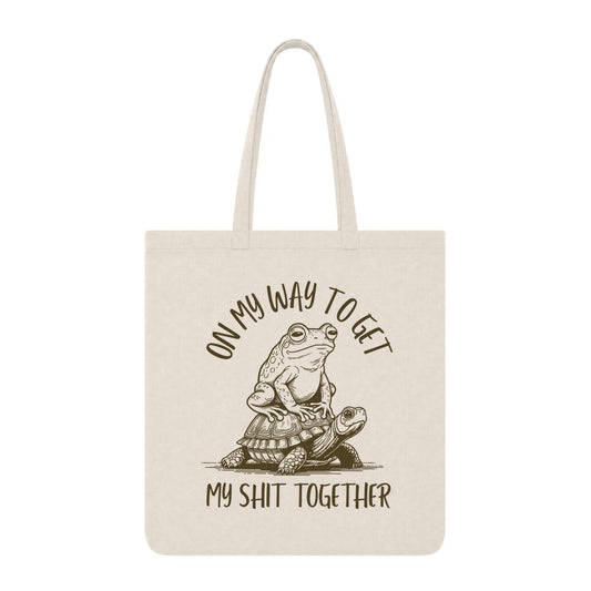 Natural tote bag with frog riding a turtle and “On My Way to Get My Shit Together” text