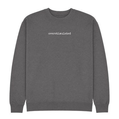 Charcoal crew neck sweatshirt with “overstimulated” printed in small white typewriter-style text across the chest.