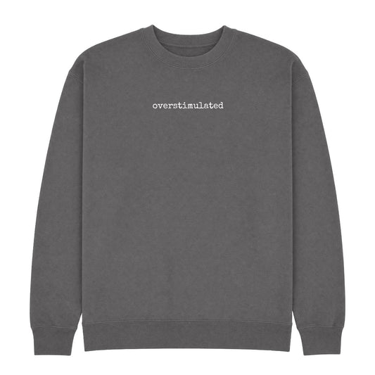 Charcoal crew neck sweatshirt with “overstimulated” printed in small white typewriter-style text across the chest.