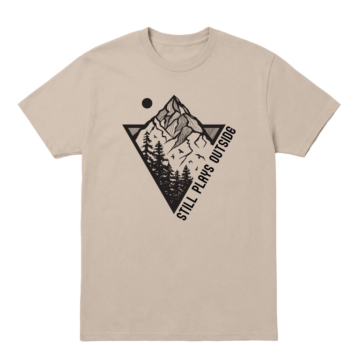 Sand T-shirt with mountain and pine tree graphic and “Still Plays Outside” text