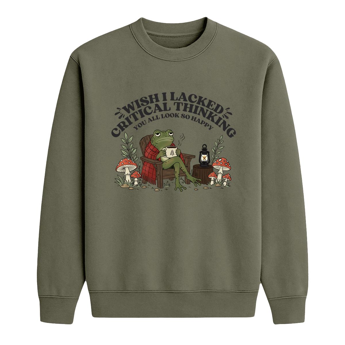 An military green crewneck sweatshirt featuring a cartoon graphic of a frog sitting in a red armchair surrounded by mushrooms, with the text 'WISH I LACKED CRITICAL THINKING YOU ALL LOOK SO HAPPY'.