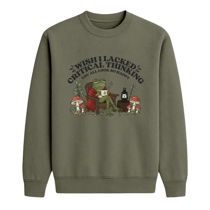 An military green crewneck sweatshirt featuring a cartoon graphic of a frog sitting in a red armchair surrounded by mushrooms, with the text 'WISH I LACKED CRITICAL THINKING YOU ALL LOOK SO HAPPY'.