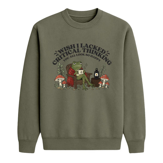 An military green crewneck sweatshirt featuring a cartoon graphic of a frog sitting in a red armchair surrounded by mushrooms, with the text 'WISH I LACKED CRITICAL THINKING YOU ALL LOOK SO HAPPY'.