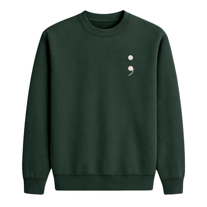 A dark forest green crewneck sweatshirt featuring a small cream semicolon symbol on the left chest, displayed on a clean white background.