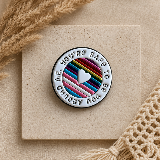 pride enamel pin with rainbow and trans colours that says you’re safe to be you around me